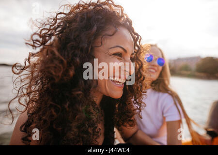 Close up shot of cheerful young woman outdoors with female friend in background.