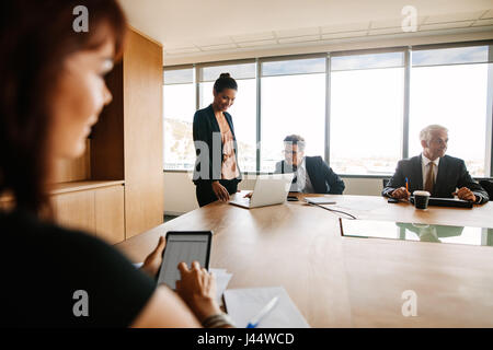 Asian businesswoman with laptop with colleagues sitting around table. Corporate business people meeting in board room.