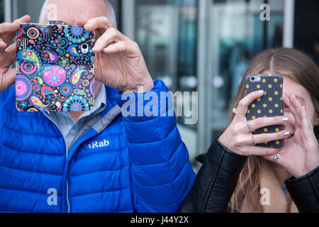 camera phones held up covering faces as man and woman take photographs Stock Photo