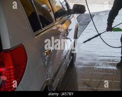The worker diligently washes the silver car Stock Photo