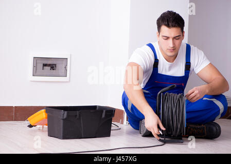 Young electrician working on socket at home Stock Photo
