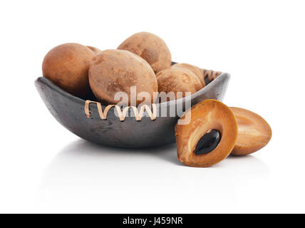 Whole and partial fresh sapodilla in bowl isolated on white background Stock Photo