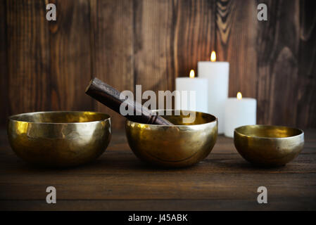 Tibetan handcrafted singing bowls with sticks on wooden background Stock Photo