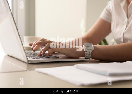 Womans hands typing on laptop at workplace Stock Photo