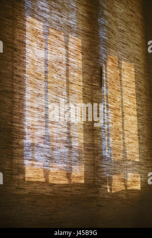 Sunlight shining through barred window on roller blind, blinds, morning. Stock Photo