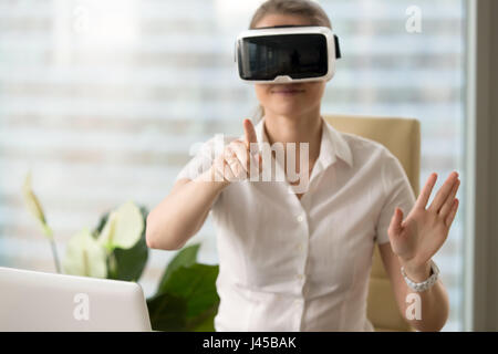 Woman in VR headset touching virtual objects Stock Photo