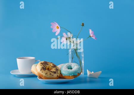 Concept beakfat. Donuts on saucer with cup of tea, flowers and origami Stock Photo