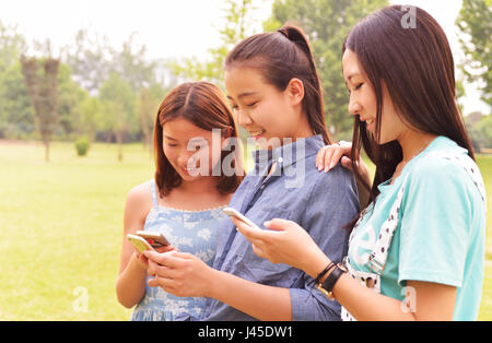 three young women use cell phones in Park Meadows Stock Photo