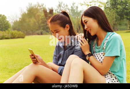 Young women use cell phones. In the Park in the morning sun Stock Photo