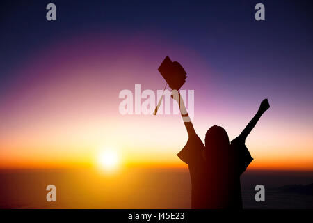 silhouette of Student Celebrating Graduation watching the sunlight Stock Photo