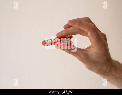 Hand spinner fidget finger toy being held between the tumb and middle finger Stock Photo