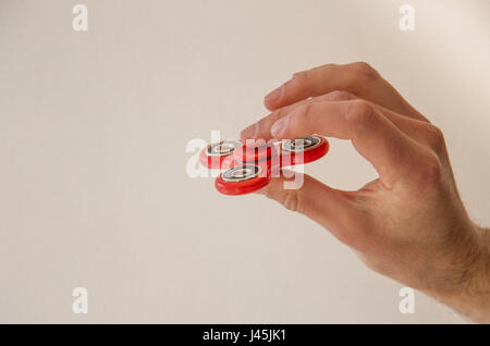 Hand spinner fidget finger toy being held between the tumb and middle finger Stock Photo