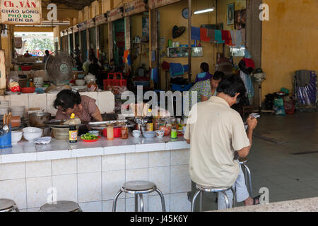 NHA TRANG, VIETNAM - JANUARY 20: Man reading newspaper in Vietnamese style food court at the Xom Moi Market in Nha Trang on January 20, 2016 in Nha Tr Stock Photo