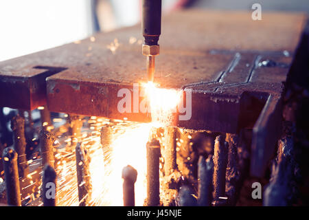 Oxygen torch cuts steel sheet. CNC gas cutting machine. Bright sparks of melting metal Stock Photo