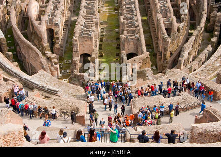 An aerial compressed perspective interior view of the amphitheatre inside the Colosseum with tourists visitors on a sunny day. Stock Photo