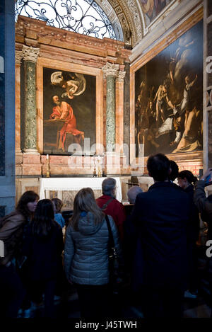Paintings by Caravaggio in the San Luigi dei Francesi church in Rome with tourists, visitors looking. Stock Photo