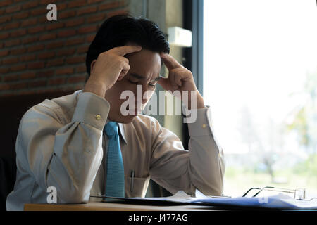 Asian businessman sitting and thinking in cafe, looking frustrated and depressed. Stock Photo