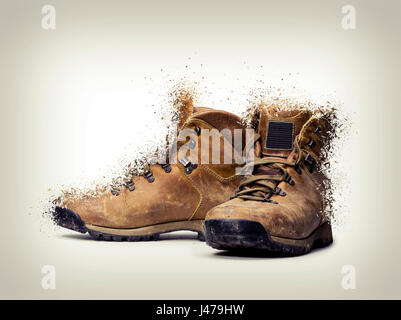 pair of hiking shoes shattered on gradient background Stock Photo