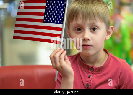 Little boy as a patriot holding in his hand a  paper flag of The United States of America. Stock Photo