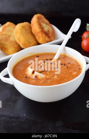 Tomato gravy for meatballs, pasta in a white bowl with potato patties on a black abstract background. Healthy food concept. Stock Photo