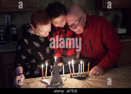 Jewish Family of grandparents and grandson lighting Hanukkah Candles in a menorah for the holdiays Stock Photo