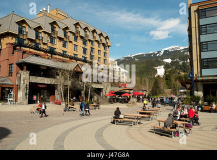 People enjoy the Whistler Village in sidewalk cafes and restaurants on a sunny day in the spring.  Whistler BC, Canada Stock Photo