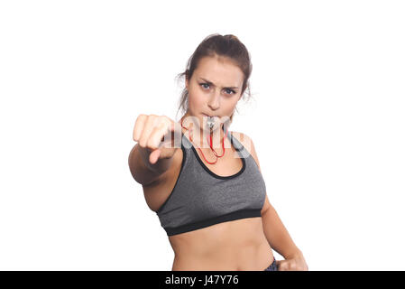 Portrait of an athlete young woman with whistle pointing to camera. Isolated white background. Stock Photo