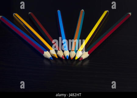 Colored pencils on a dark wooden background, arranged fan-shaped Stock Photo