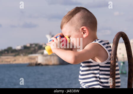 dreaming small boy looking into the distance through binoculars Stock Photo