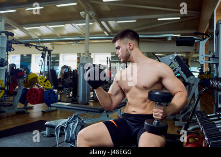 The guy is doing exercises with dumbbells in the gym Stock Photo