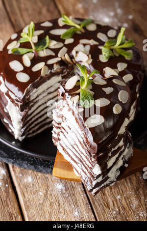 piece of chocolate crepe cake with whipped cream and almonds close-up on a table vertical Stock Photo