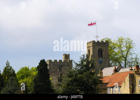 English flag on St Nicholas church beside 15th century Marmion Tower gatehouse to lost manor house. West Tanfield North Yorkshire England UK Britain Stock Photo