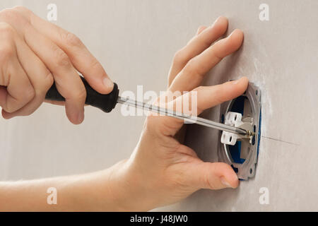 hands installing light switch with screwdriver in plasterboard wall Stock Photo