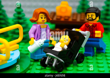 Tambov, Russian Federation - September 21, 2016 Lego family on a picnic in park with playground. Lego family minifigures - father, mother and baby in  Stock Photo