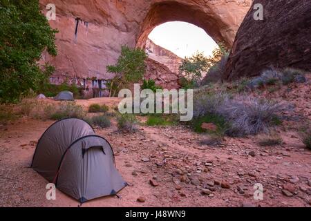 Tent and Wilderness Camping on Great Hiking Trail under Jacob Hamblin Arch. Coyote Gulch Rock Landscape Canyons of the Escalante, Utah, United States Stock Photo