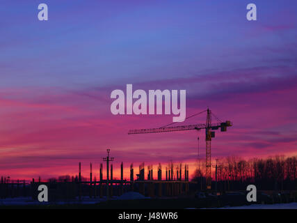 Construction Site. Industrial construction cranes and building silhouettes on night sky. Beautiful colorful night landscape. Stock Photo