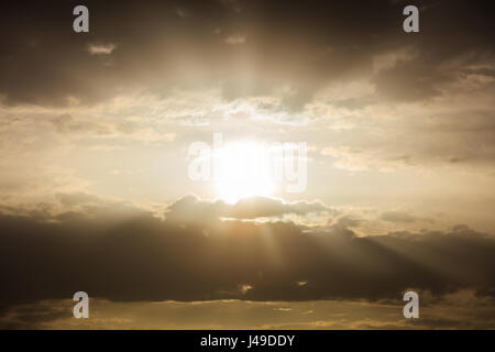Light beams shining trough the clouds at sunset Stock Photo