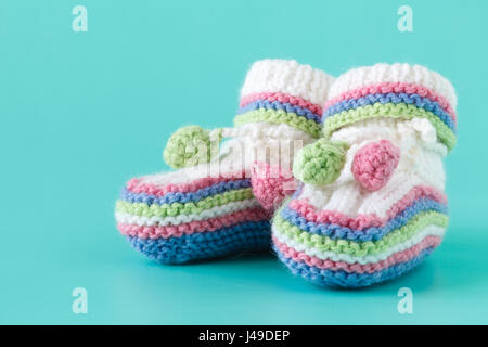 Newborn announcement. knitted baby booties on plain aquamarine background Stock Photo