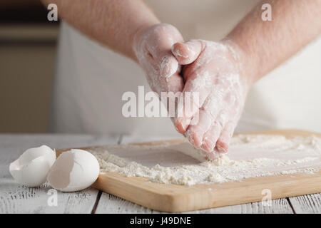 Flour on light wooden table like background with man's hand. Selective focus. Stock Photo