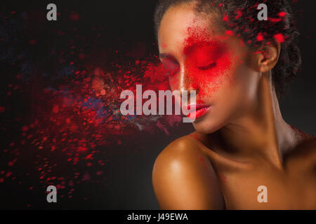 Fashion makeup. Close-up face of a beautiful young woman with splashes of red paint on a black background Stock Photo