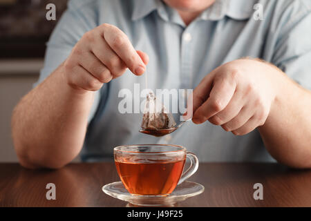 Teabag in the cup with hot water in hands Stock Photo