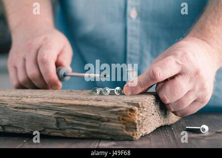 screws on wood in male hands, closeup view Stock Photo