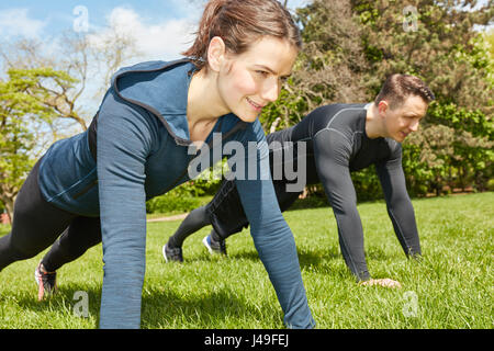 Man and woman doing push ups at the park for training Stock Photo