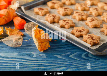 Delicious homemade cookies in the form of a maple leaf, oak leaves, acorns and hedgehog on wooden background. Stock Photo