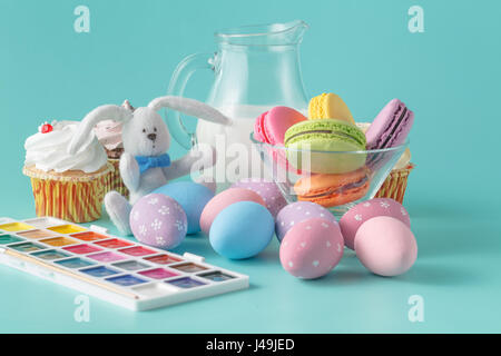 Easter breakfast with milk and french macaroon, painted egg on aquamarine background Stock Photo