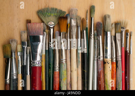 A collection of well used art paint brushes on wood Stock Photo