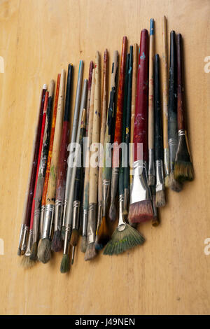 A collection of well used art paint brushes on wood Stock Photo