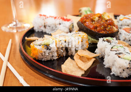 A large sushi platter, served on a round plate with tuna tartare in the center and the accompanying crisps. Stock Photo