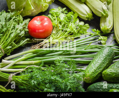 Fresh vegetables and greens in bunches arranged in a frame on a black stone background. Top view with space for text. Stock Photo