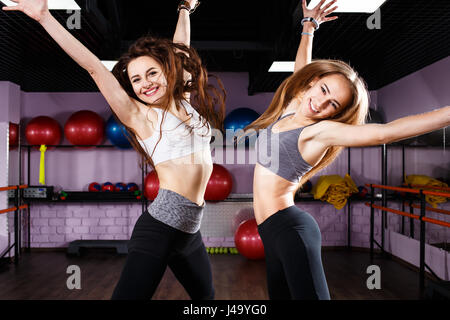 Two excited fitness girls jumping in health center. Laughing young happy women have fun in the gym Stock Photo